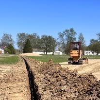 A bulldozer is digging a trench in the dirt.