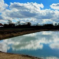 A large body of water with a blue sky and clouds reflected in it.