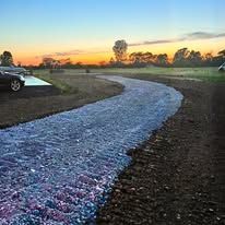 A car is parked on the side of a dirt road.