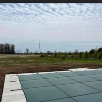A swimming pool cover is sitting on top of a tiled floor in a field.