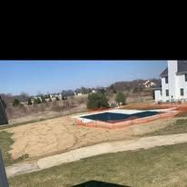 A large swimming pool is being built in the backyard of a house.