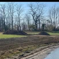A field with a lot of dirt and trees in the background.