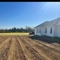 A white house is sitting in the middle of a dirt field.