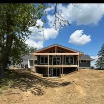 A large house is being built in the middle of a dirt field.