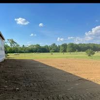 There is a large field in the background and a building in the foreground.