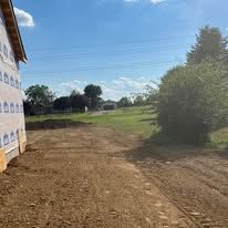 A dirt road leading to a house under construction.