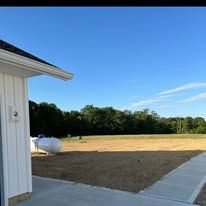 A small plane is parked in a field next to a building.
