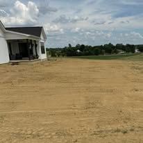 A house is sitting in the middle of a dirt field.