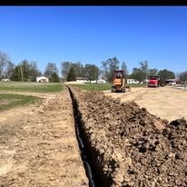 A tractor is digging a trench in the dirt in a field.