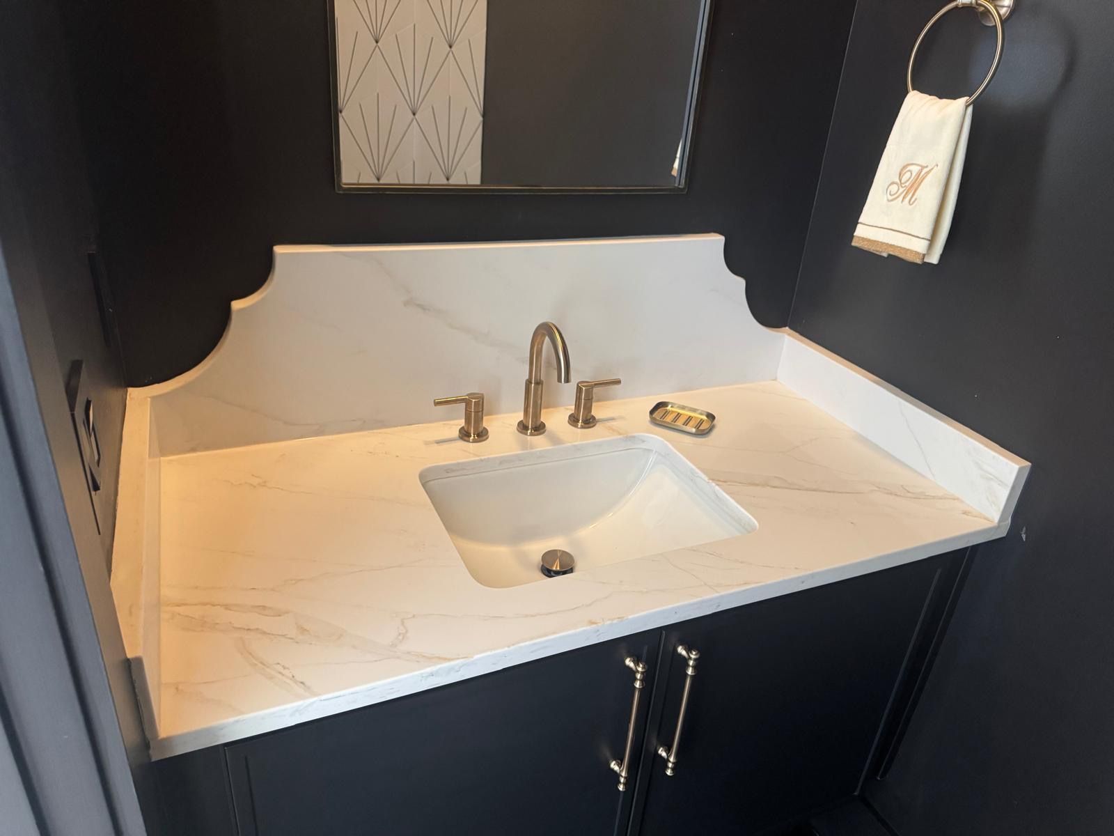 White bathroom vanity with sink, chrome faucet, dark cabinets, and wall mirror under cabinet lighting