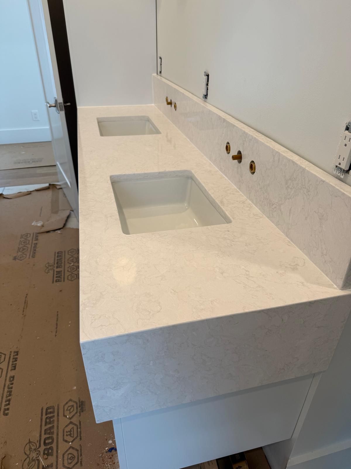 Bathroom vanity countertop with two rectangular sinks and faucet holes, still under construction