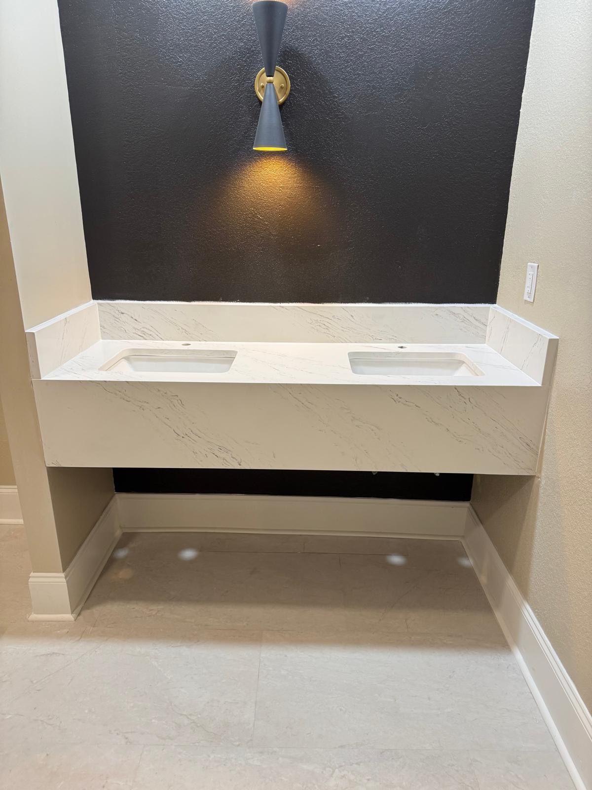 Modern bathroom vanity with double sinks, black accent wall, and warm wall sconce lighting