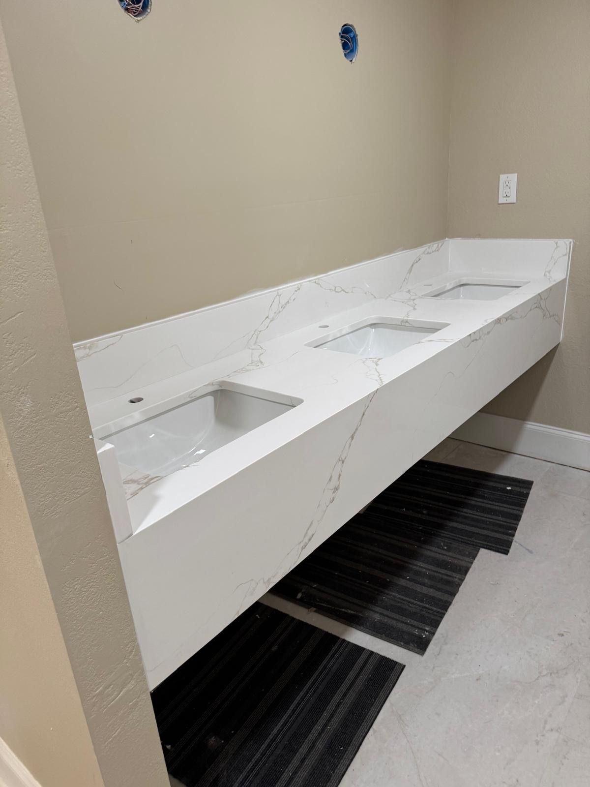 Modern double-sink bathroom countertop with white sinks and beige walls
