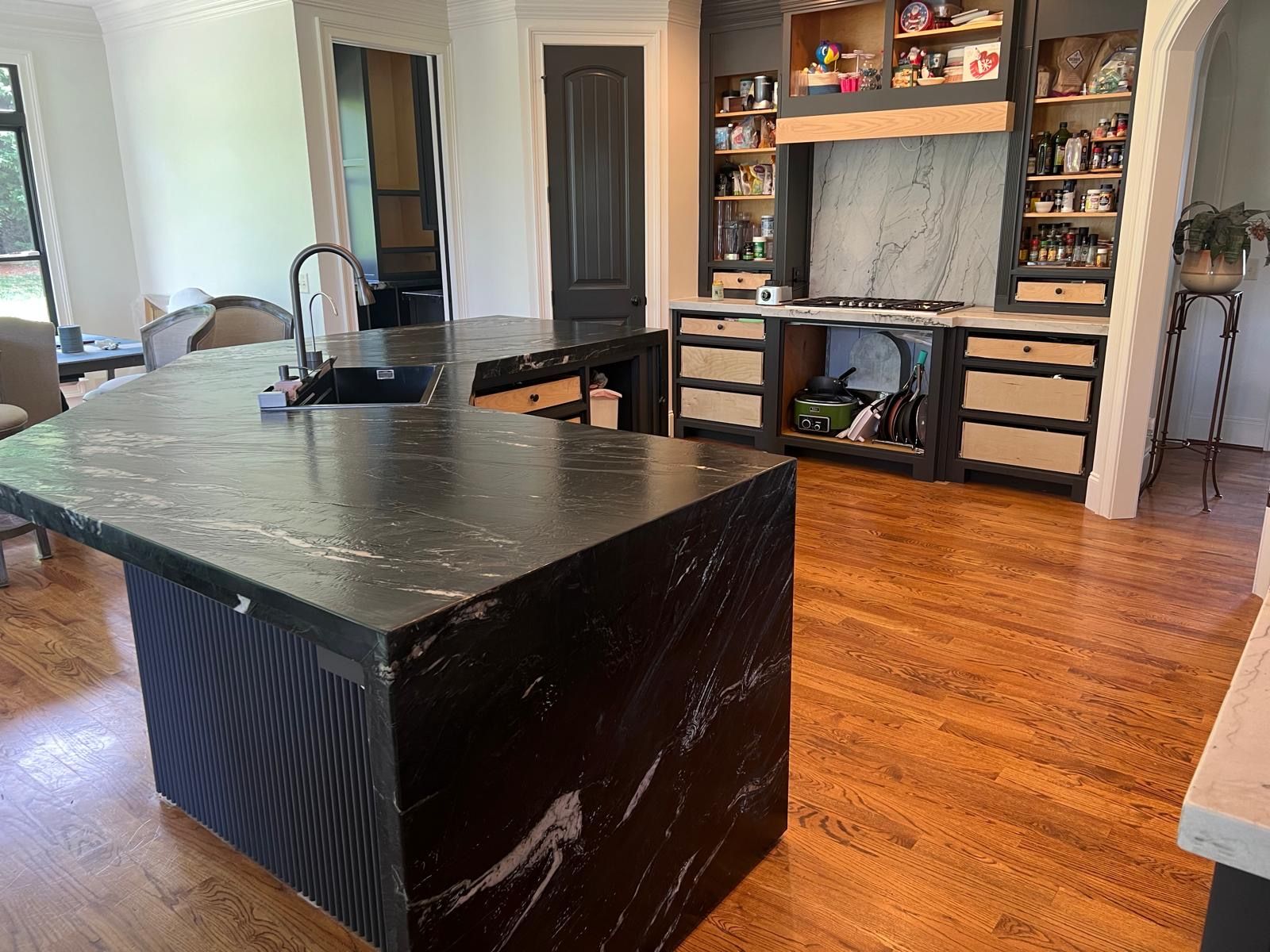 Modern kitchen with black island, hardwood floors, and built-in cabinetry