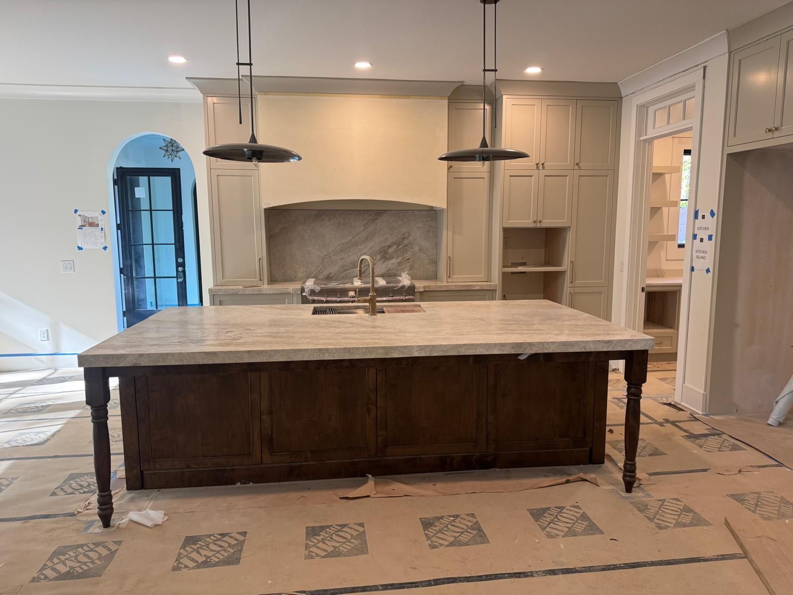 Modern kitchen with large island, pendant lights, and open shelving under construction