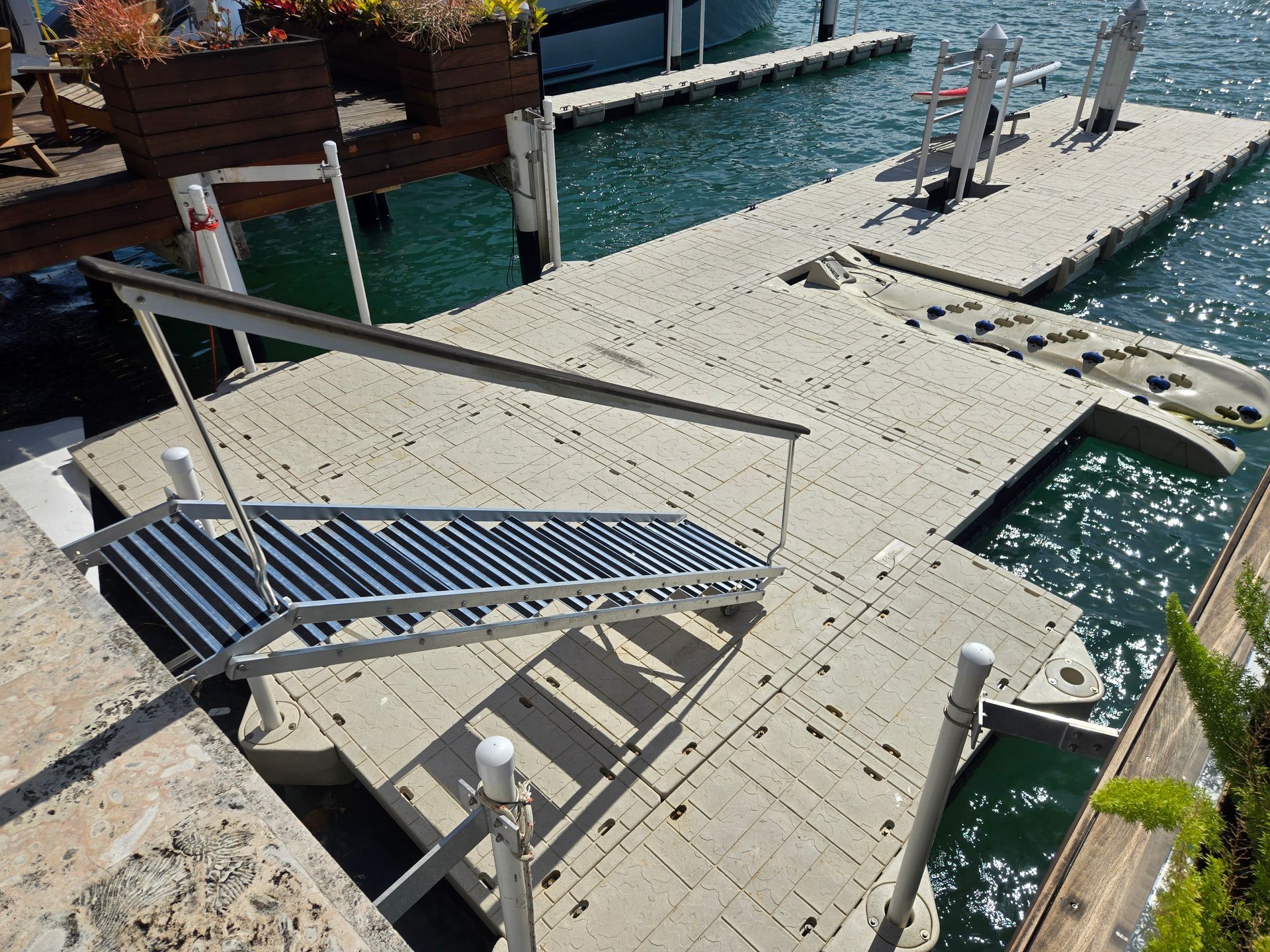 A series of interconnected, light-colored docks with a set of stairs leading to the water.