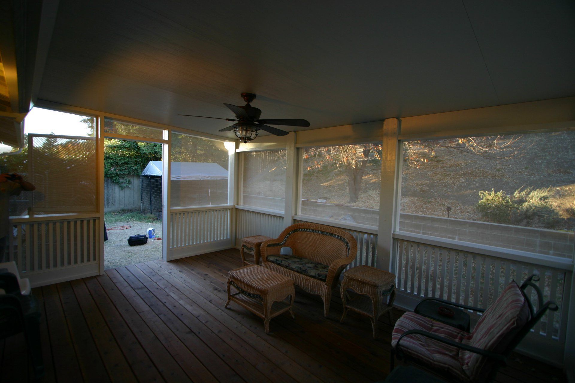 A screened in porch with furniture and a ceiling fan