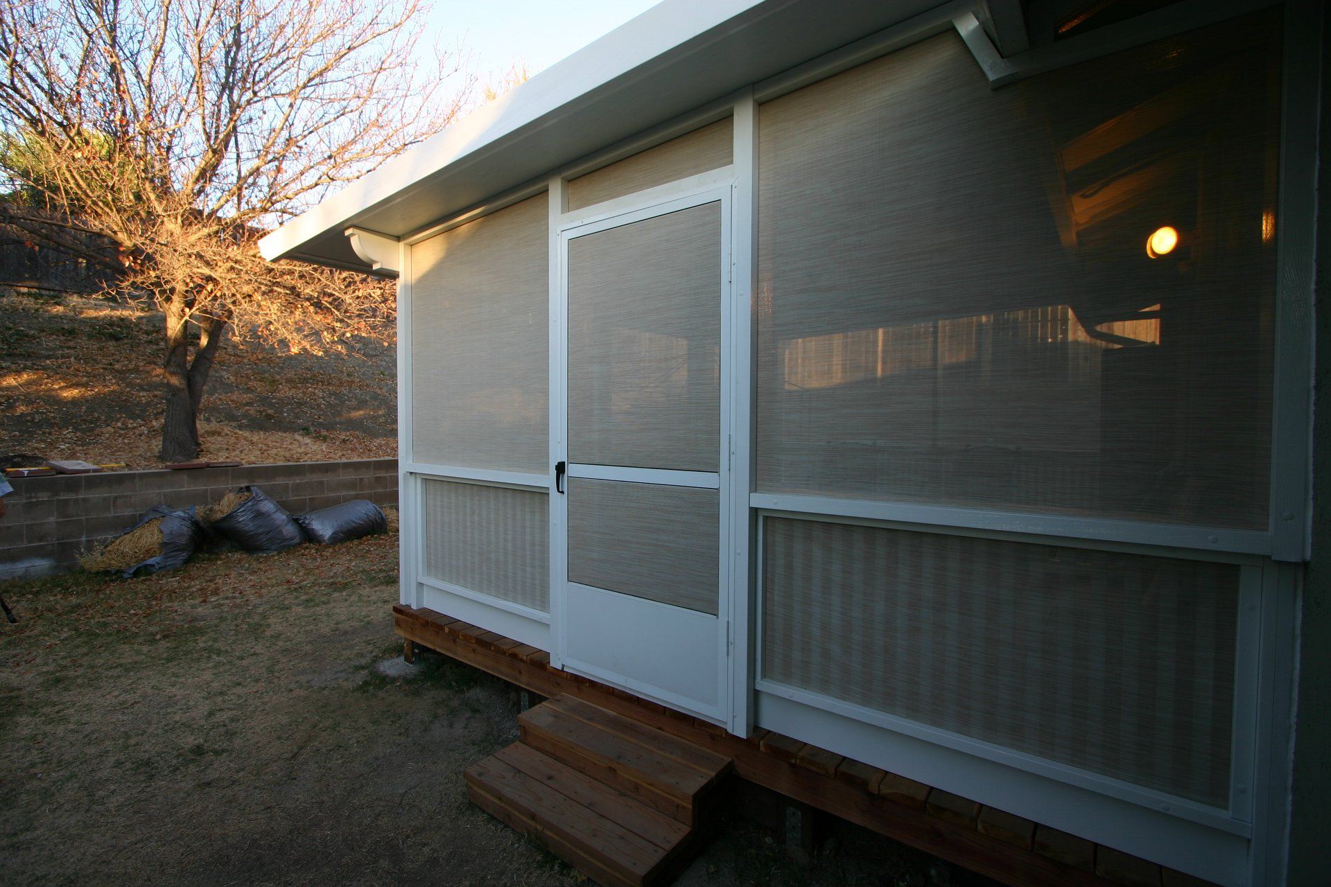 A screened in porch with a white door and steps