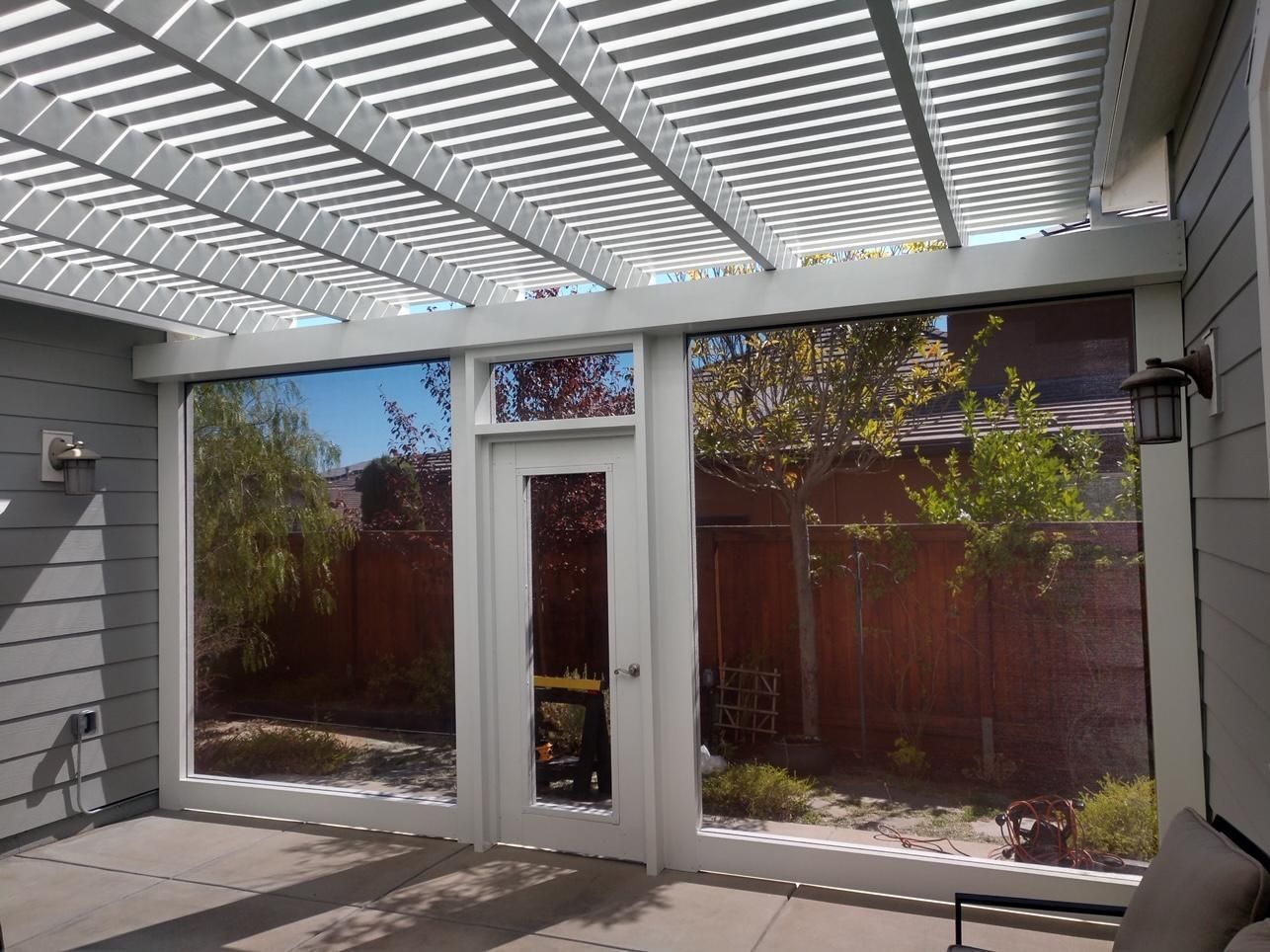 A patio with a pergola and lots of windows