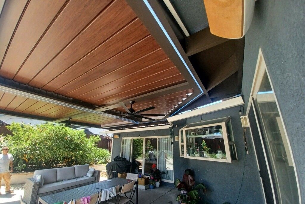 A patio with a wooden ceiling and a ceiling fan.