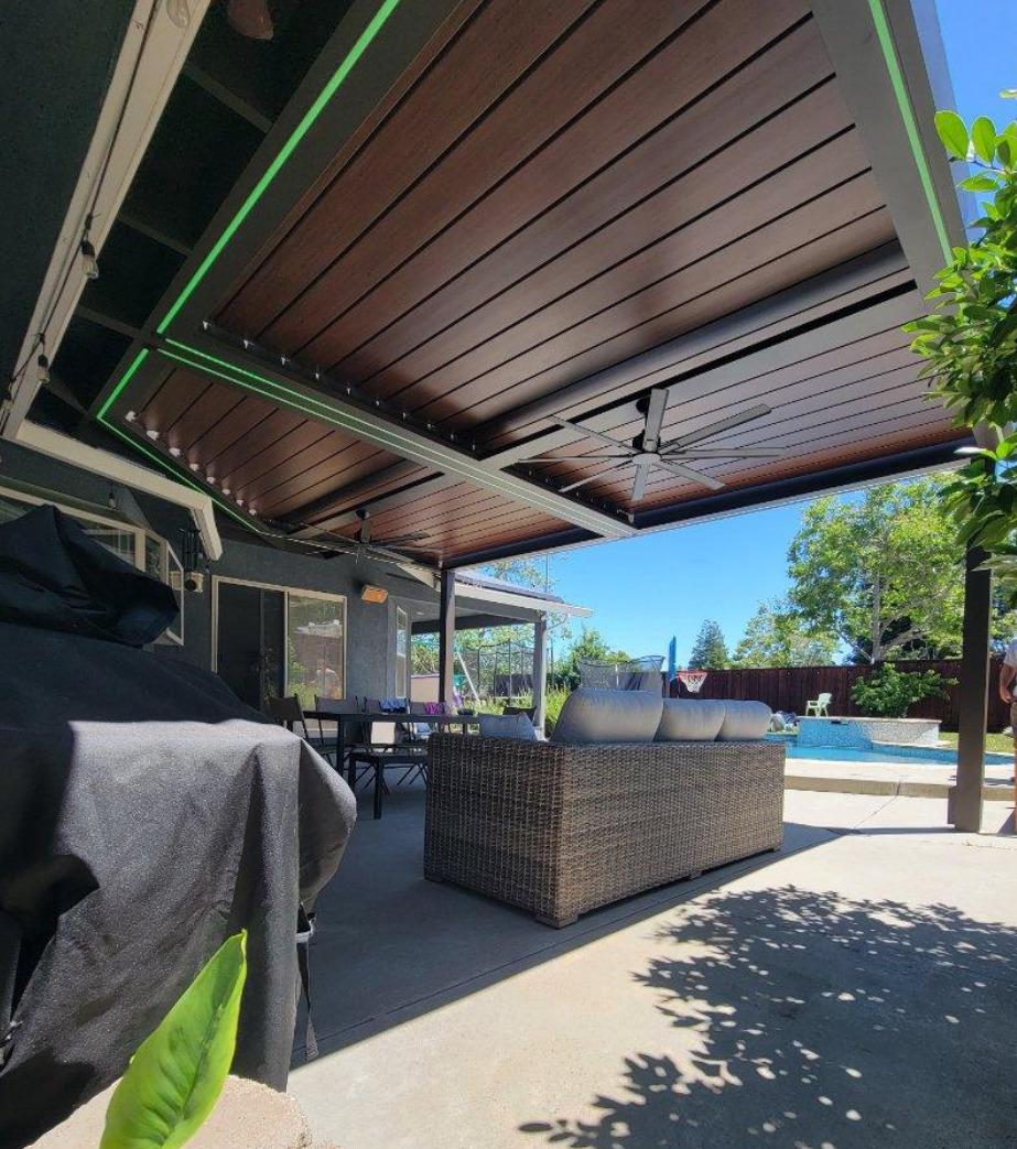 A patio with a couch and a grill under a canopy