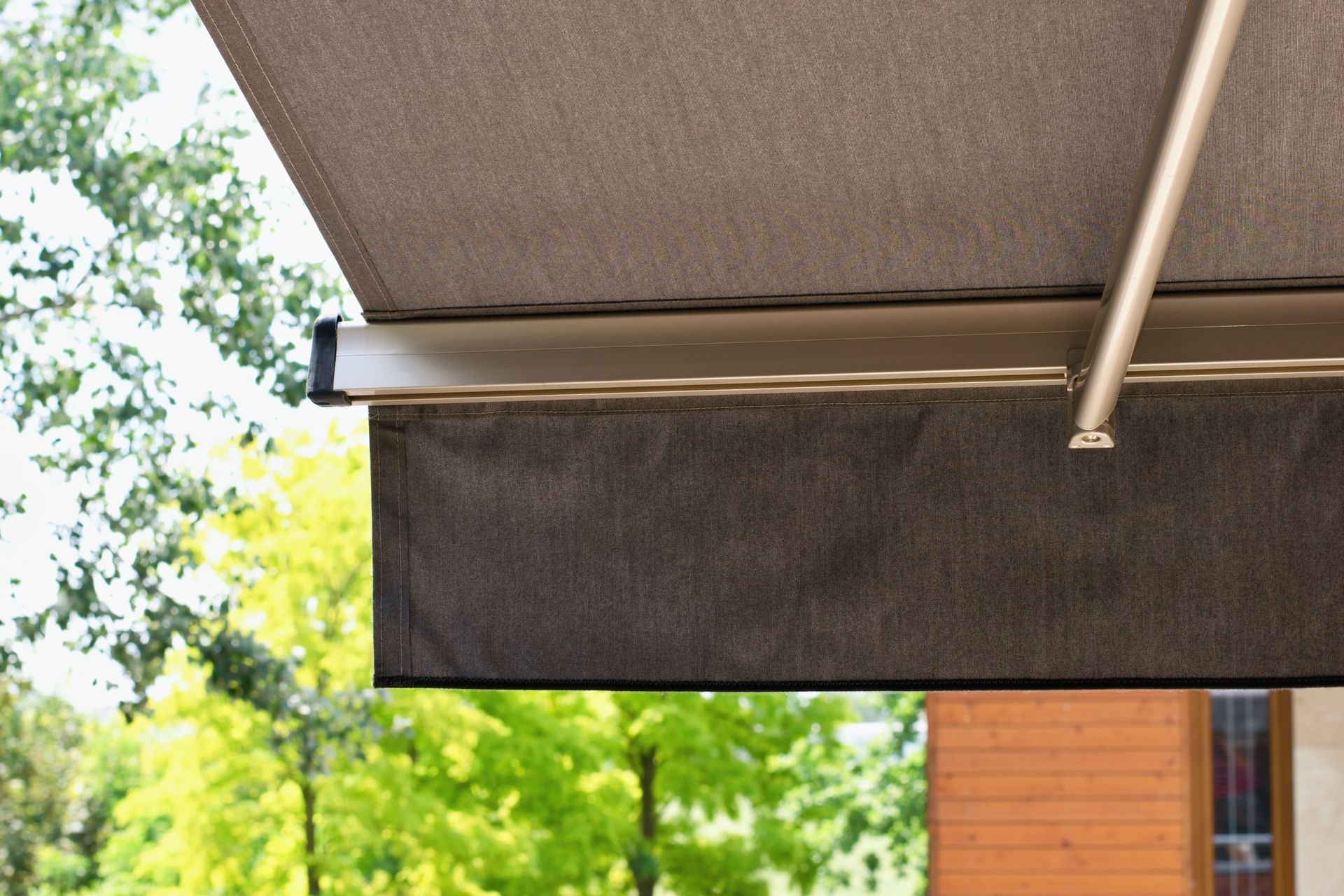 A close up of an awning on a porch with trees in the background.