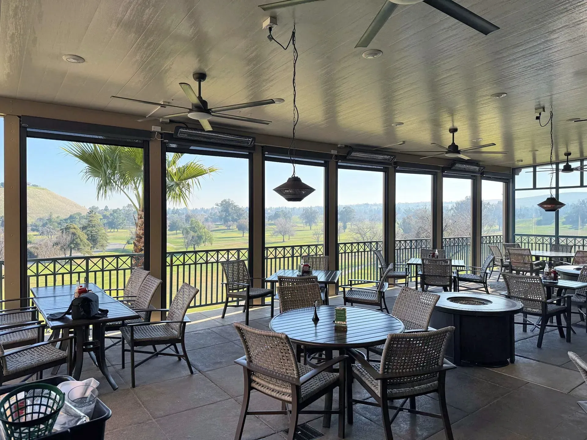 A restaurant with tables and chairs and a view of a golf course.