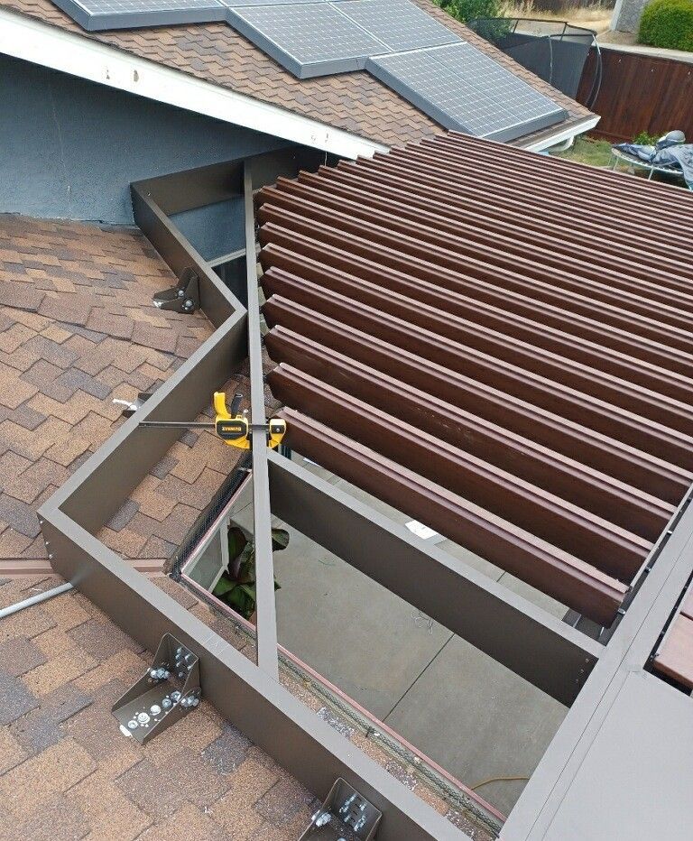A pergola is being installed on the roof of a house