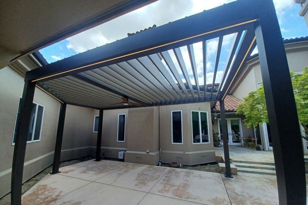 A pergola is sitting in the backyard of a house.
