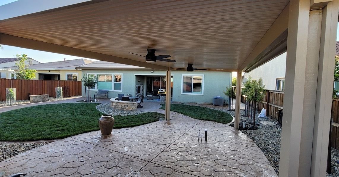 A backyard with a covered patio and a house in the background.