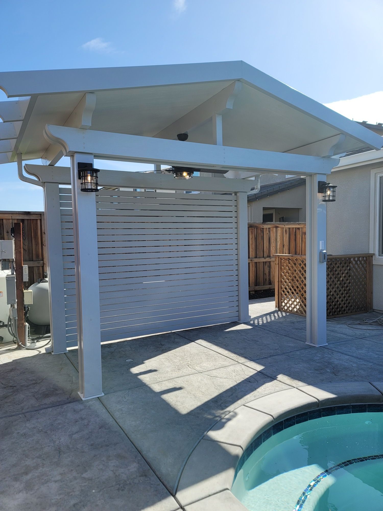 A white pergola is sitting next to a pool.