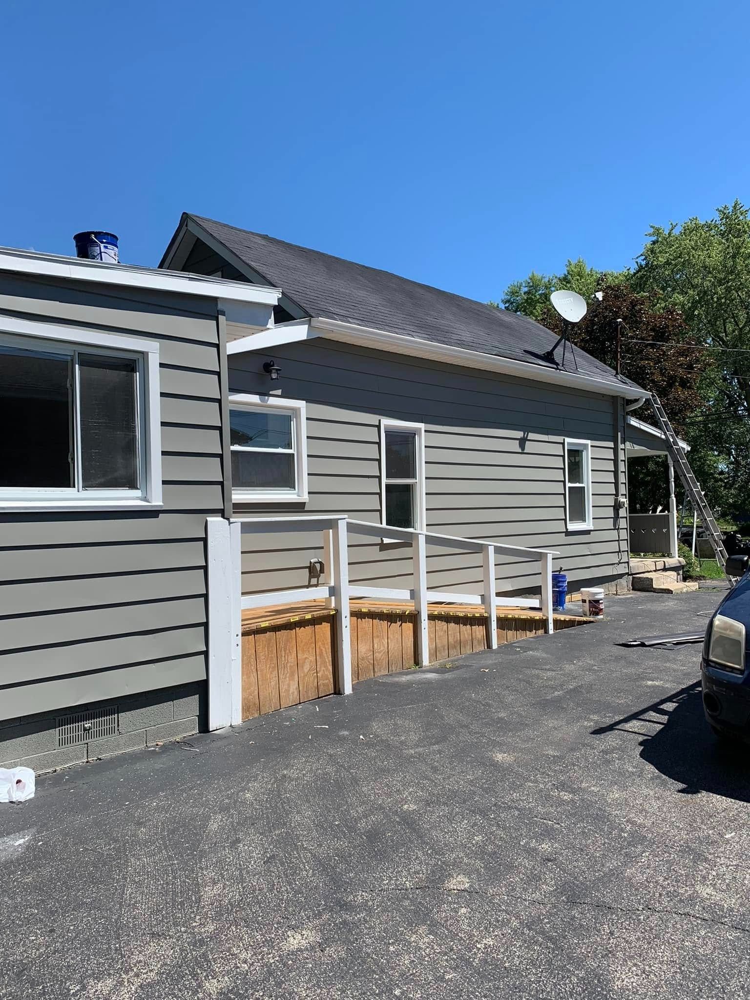 Gray house exterior with white trim and small porch under a blue sky