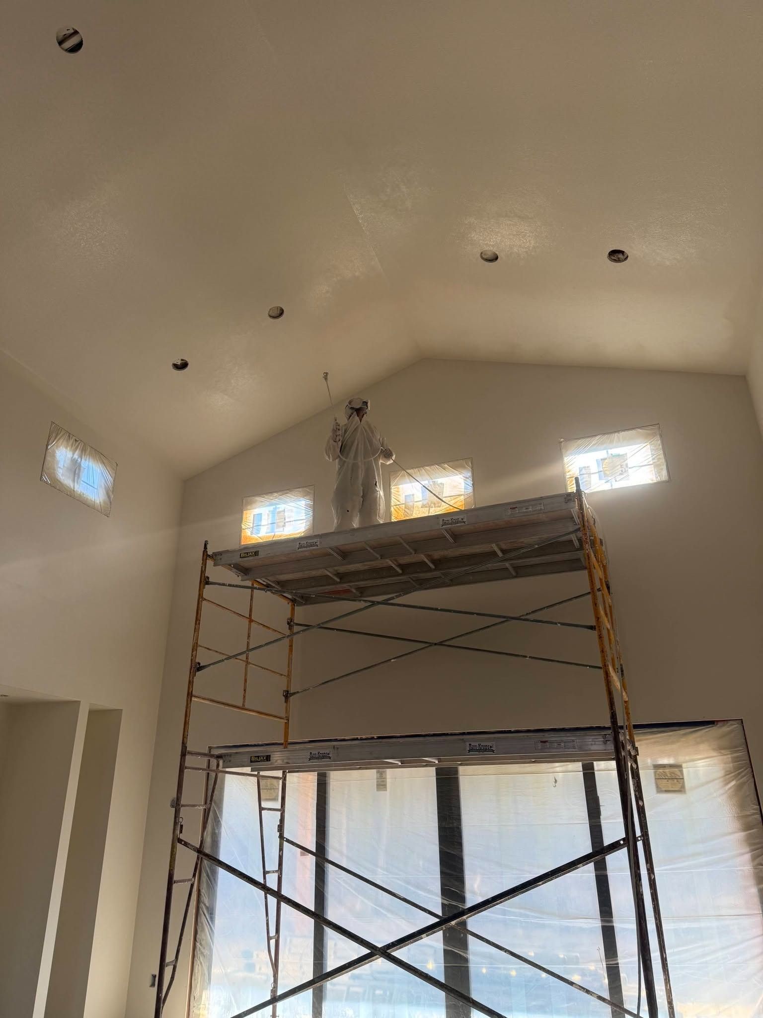 Interior room with tall scaffolding under a vaulted ceiling and small high windows.