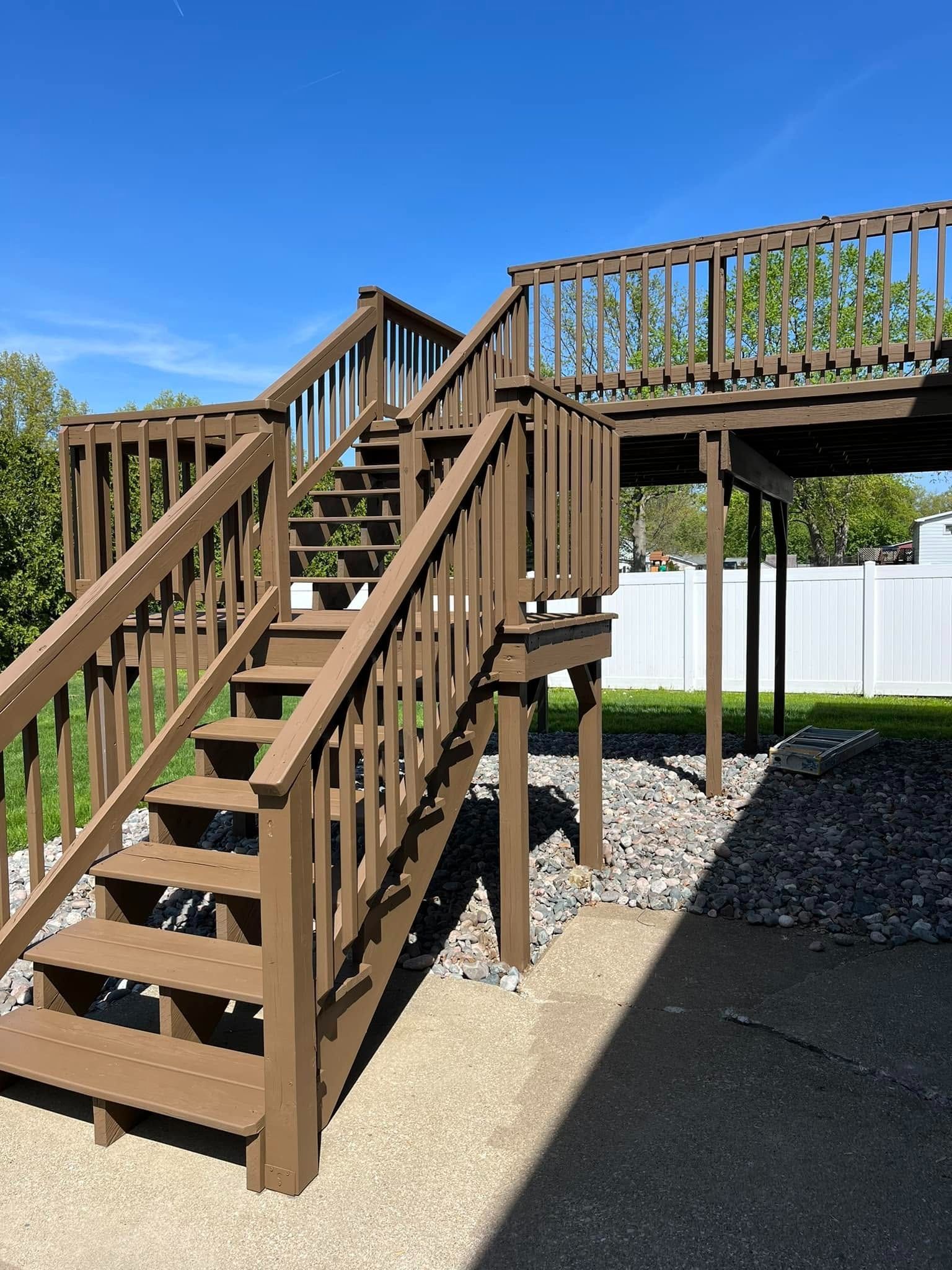 Brown wooden staircase leading to an elevated deck in a sunny outdoor playground area