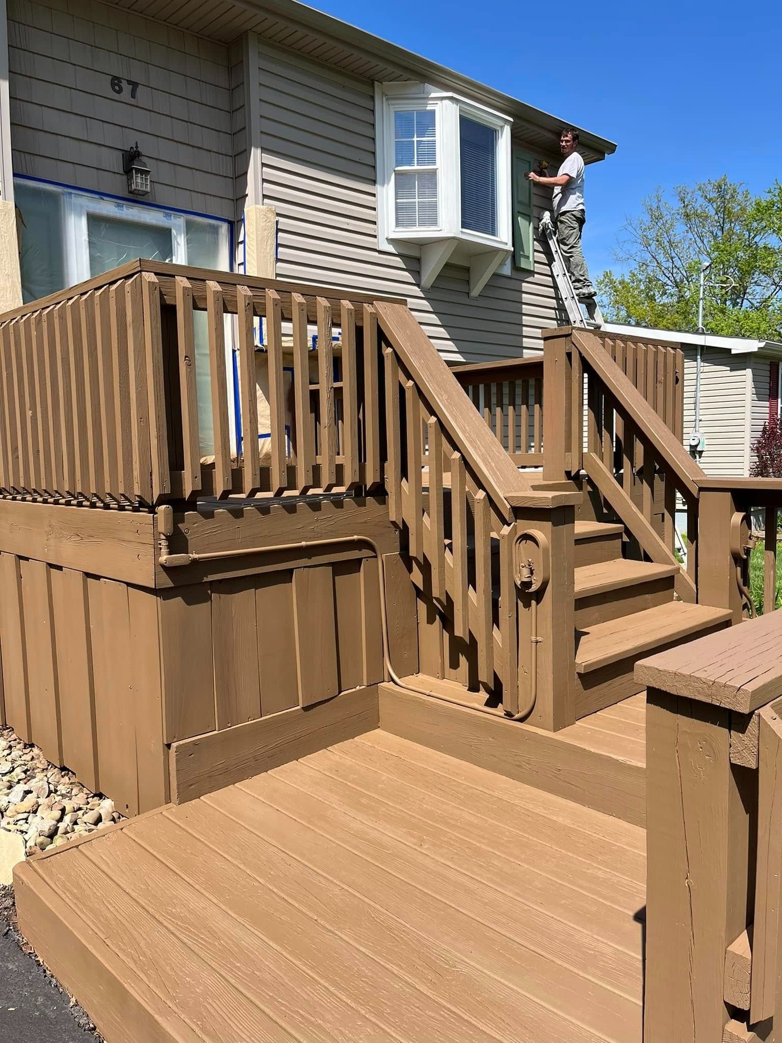 Wooden deck and stairs attached to a house with a person standing on the upper landing