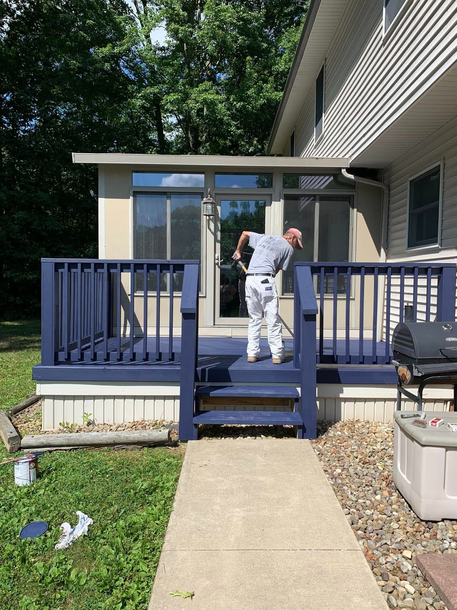 Person standing on a blue porch steps in front of a house, reaching toward the door.