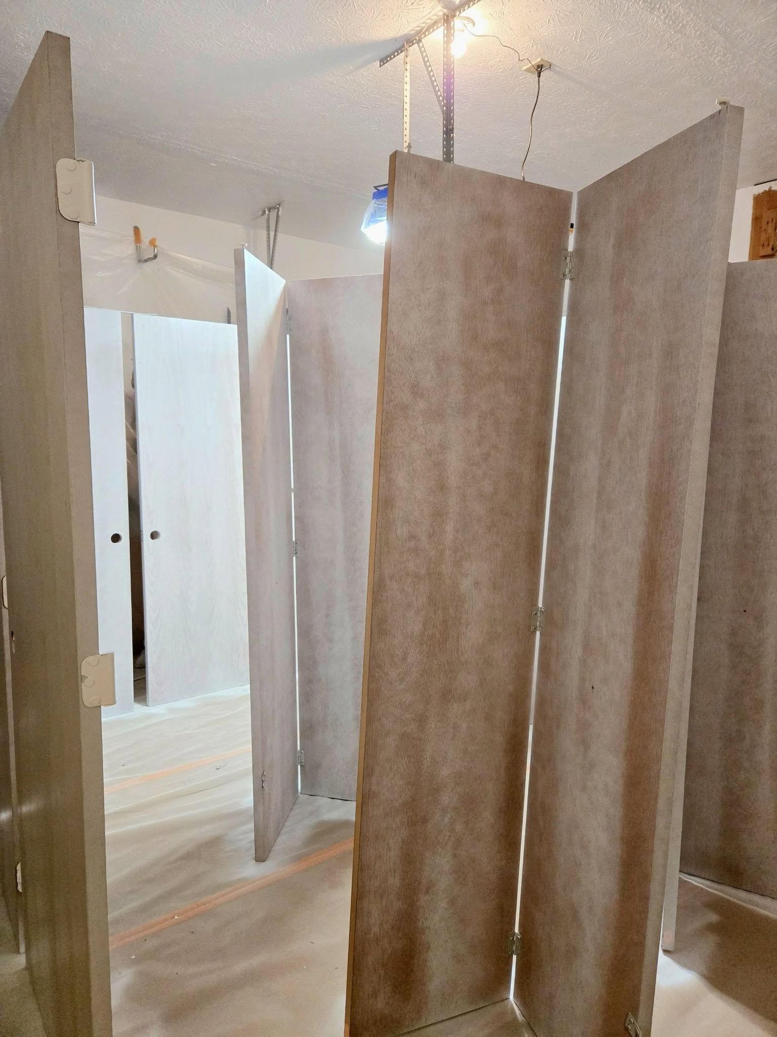 Row of beige changing-room stalls with curtains in a bright indoor hallway