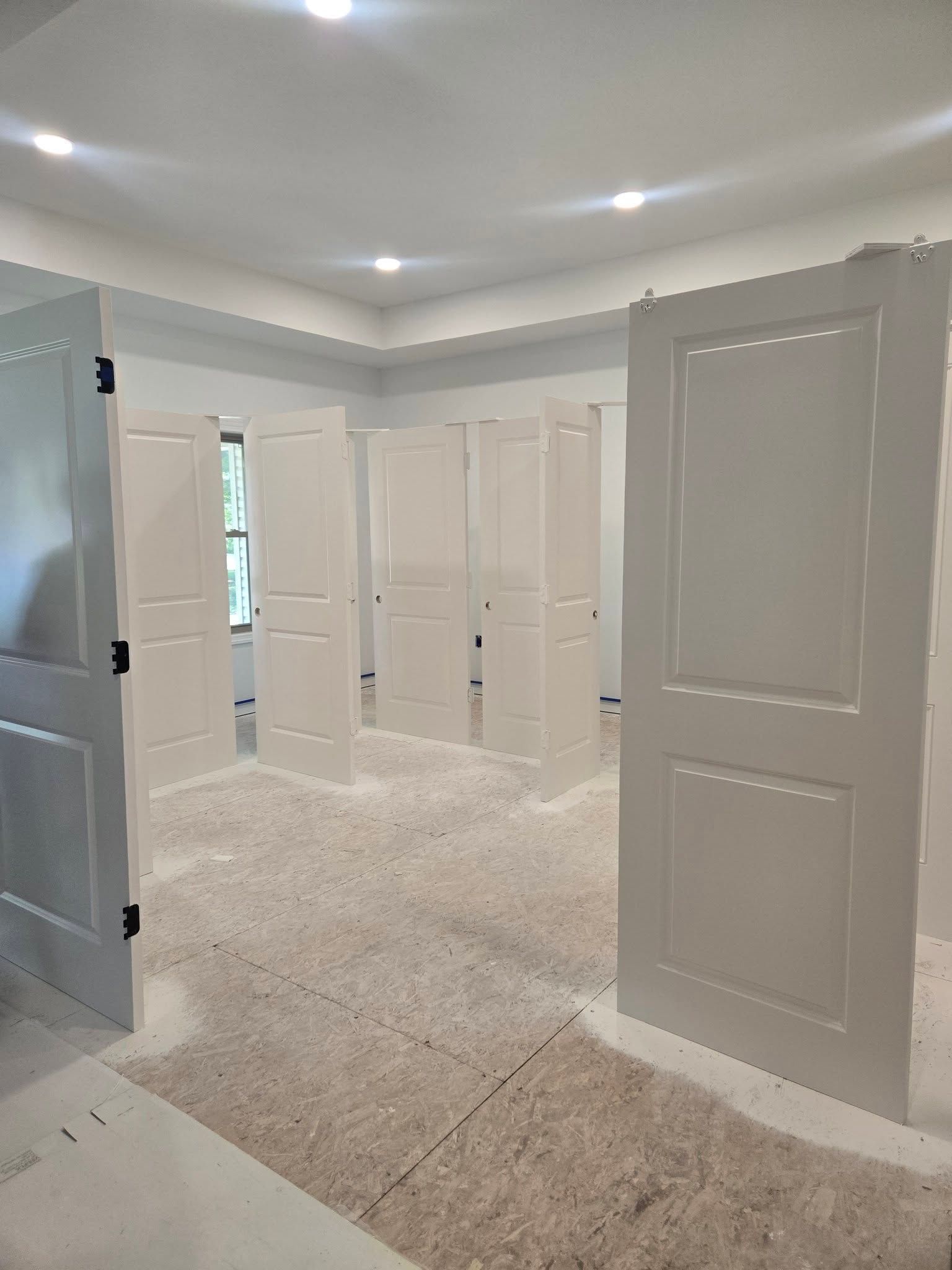 Bright white carpeted room with open paneled doors and recessed ceiling lights