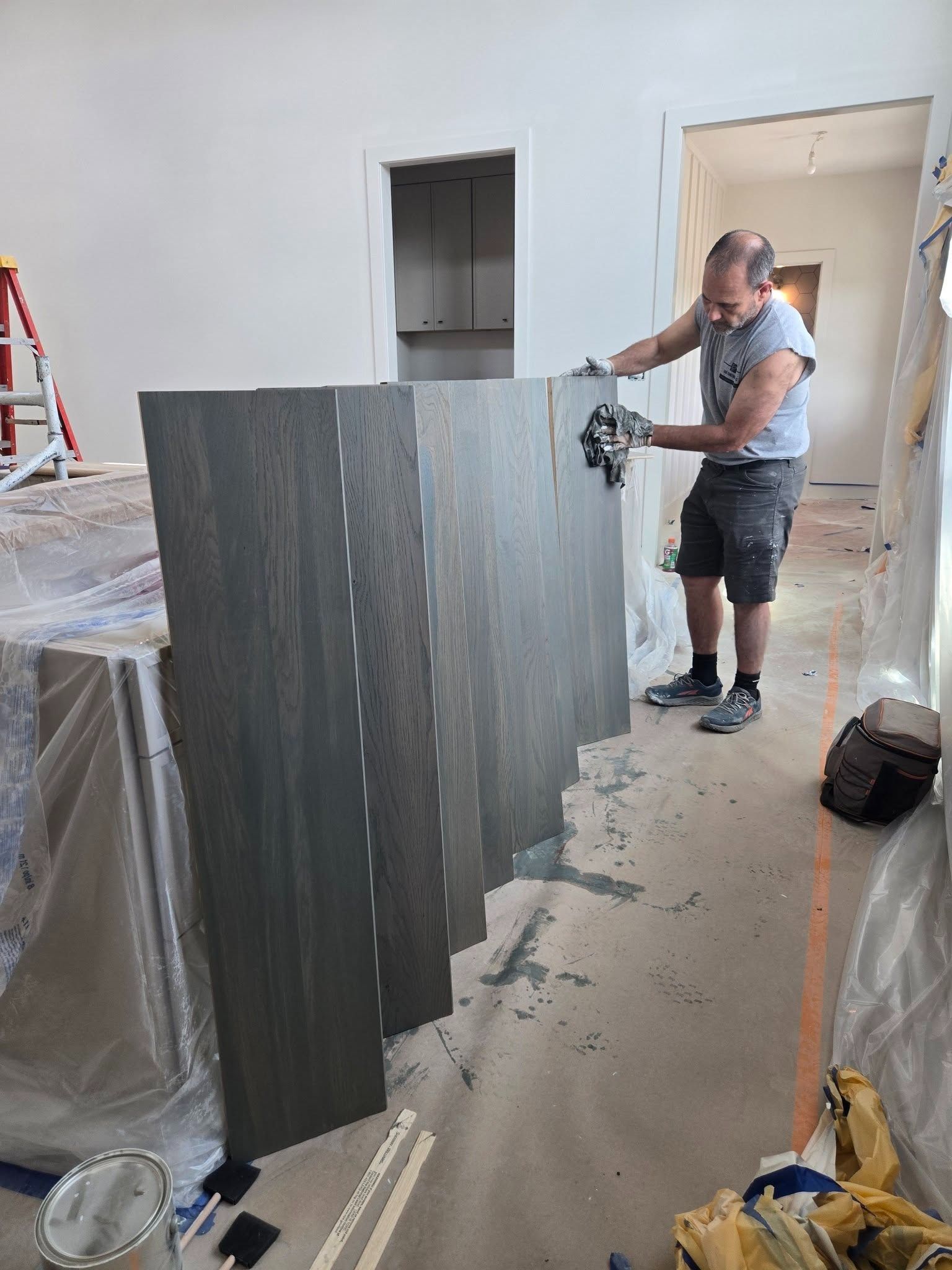 Worker installing gray wall panels in a room under renovation