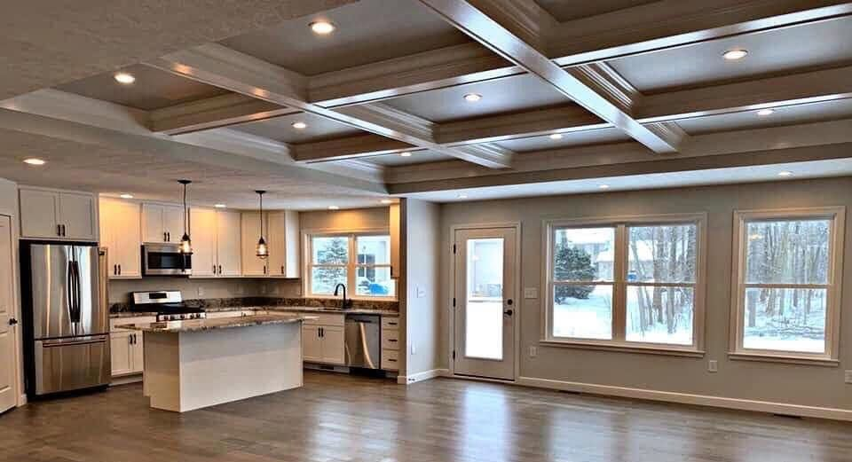 Open-concept kitchen and living area with white cabinets, island, wood floors, and large windows