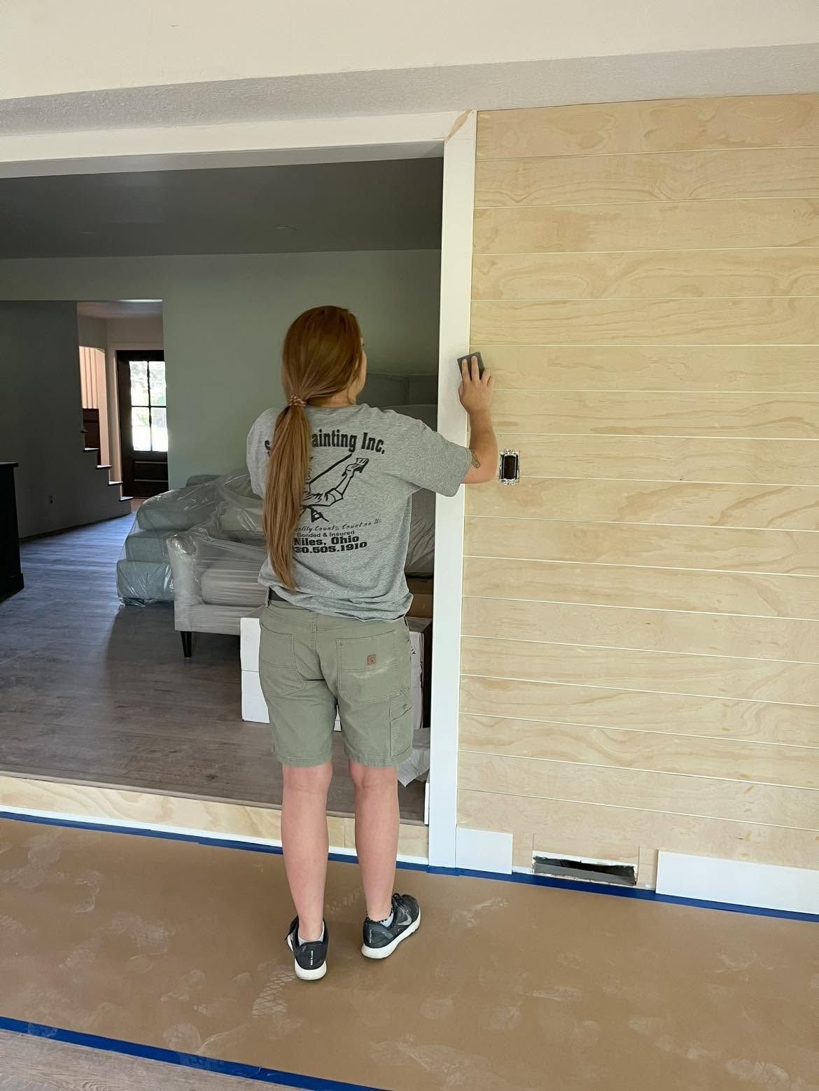 Person painting a white wall beside a large doorway in an unfinished room