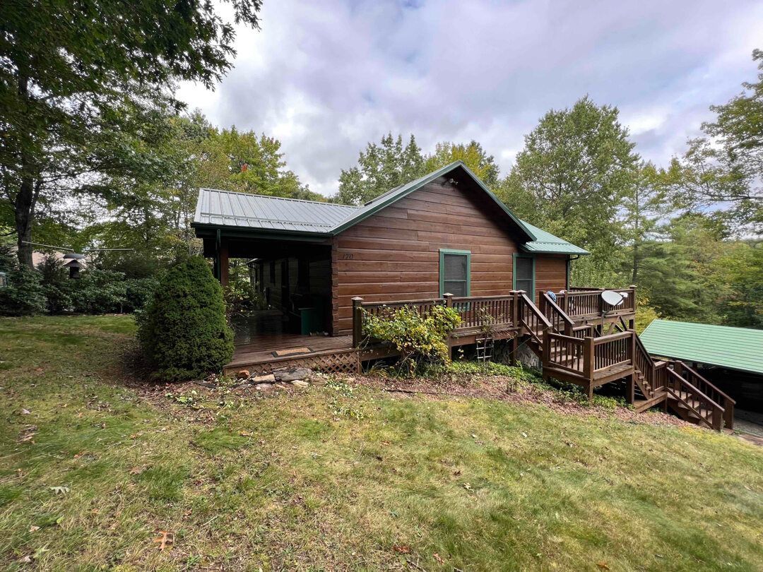 a small log cabin with a green roof and stairs is sitting in the middle of a grassy field .