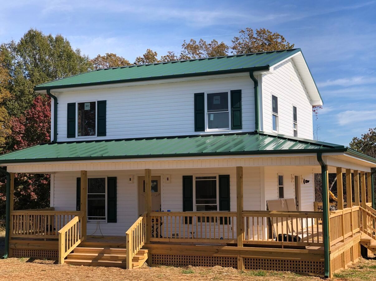 a white house with a green roof and a large porch .