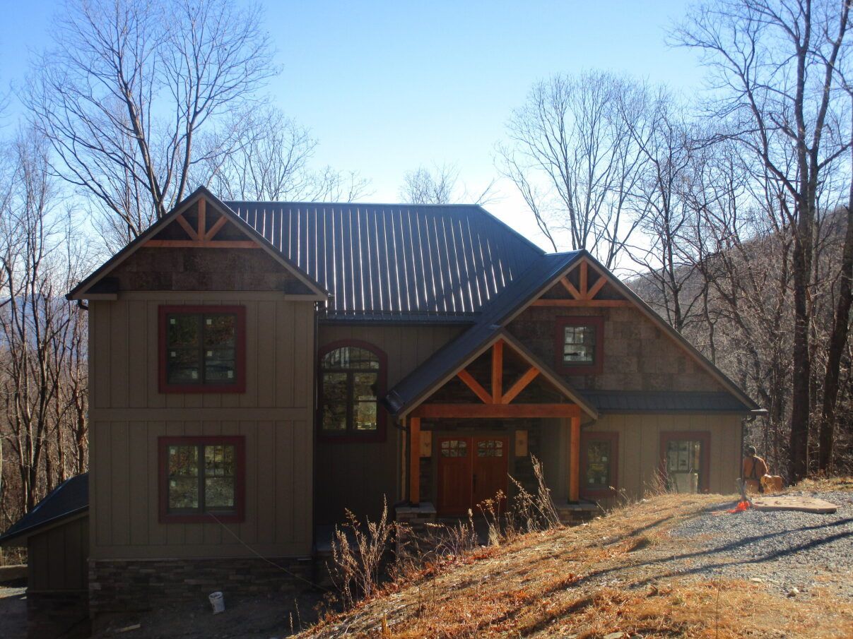 a large house with a metal roof is surrounded by trees