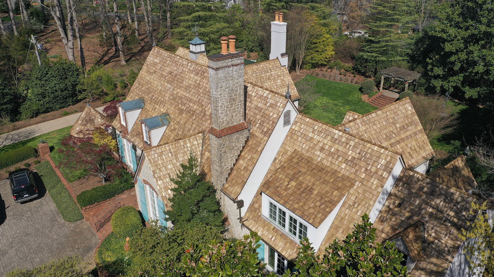 An aerial view of a large house with a thatched roof surrounded by trees.