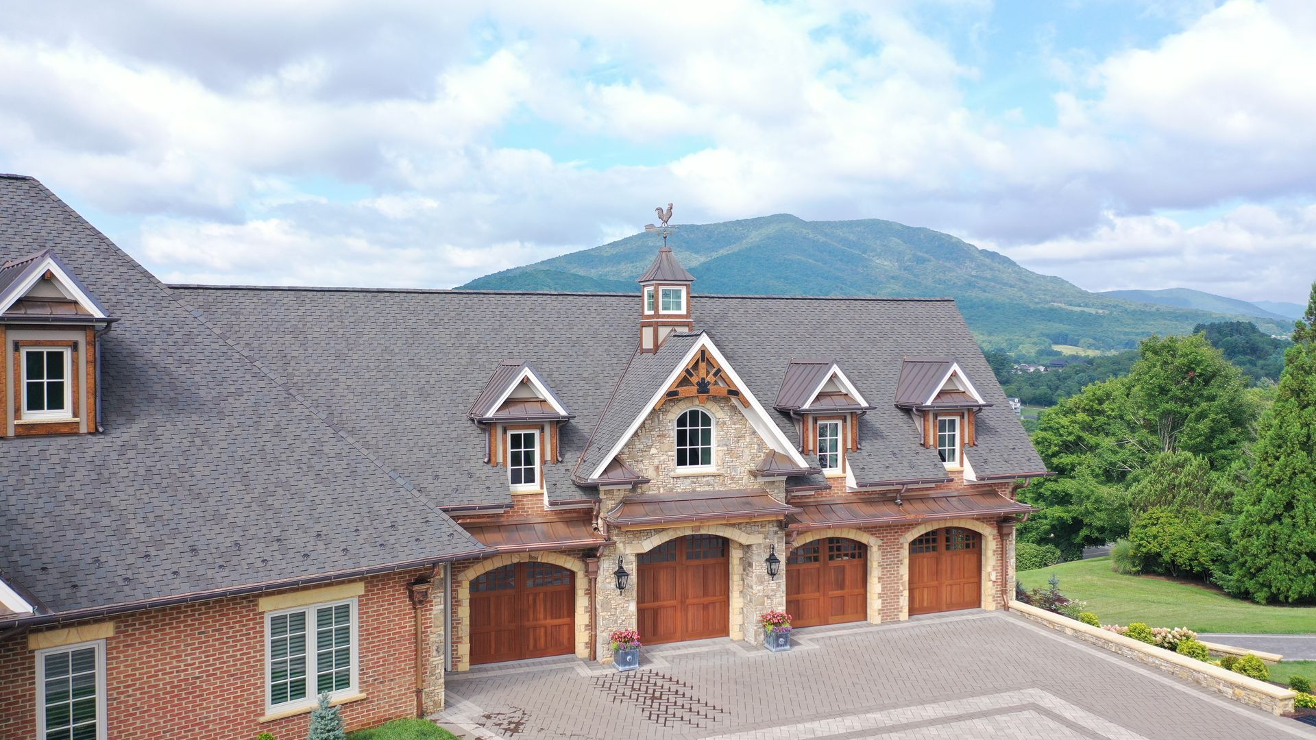 Luxury garage with brown doors and stone accents against a mountain backdrop.