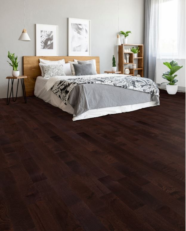 A bedroom with a bed and a wooden floor