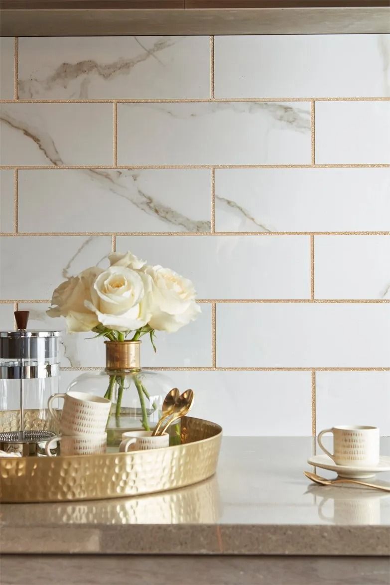A gold tray with a vase of flowers on it is on a counter.