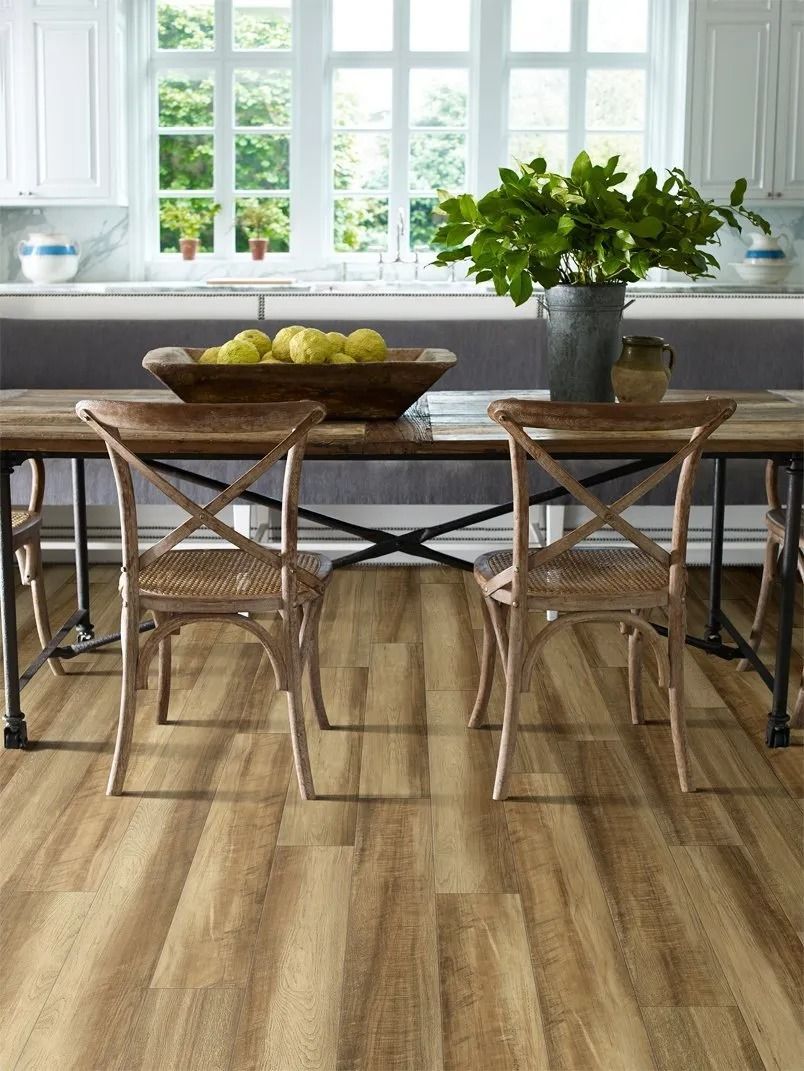 A dining room with a wooden table and chairs and a potted plant on the table.