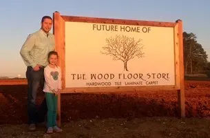 Man and his daughter standing beside the sign